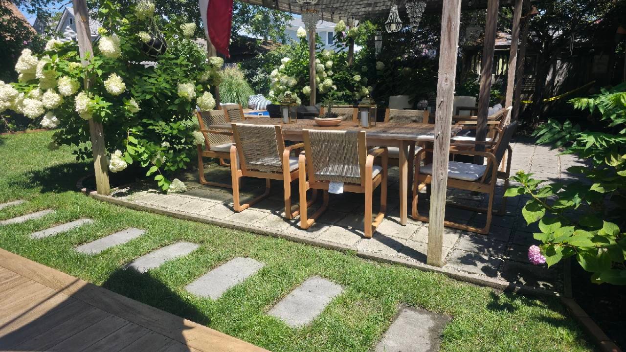 Hydrangea-framed outdoor dining patio with lawn and stepping-stone path